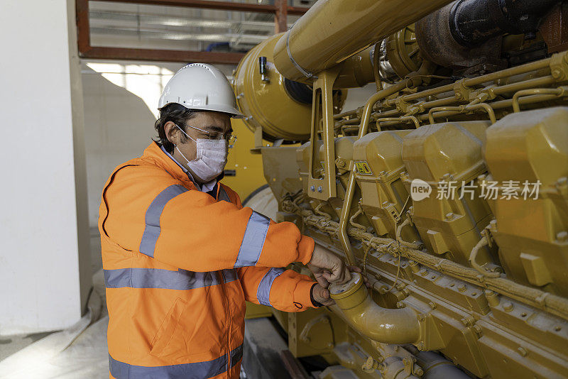 Engineer wearing protective workwear controls the machinery in the factory